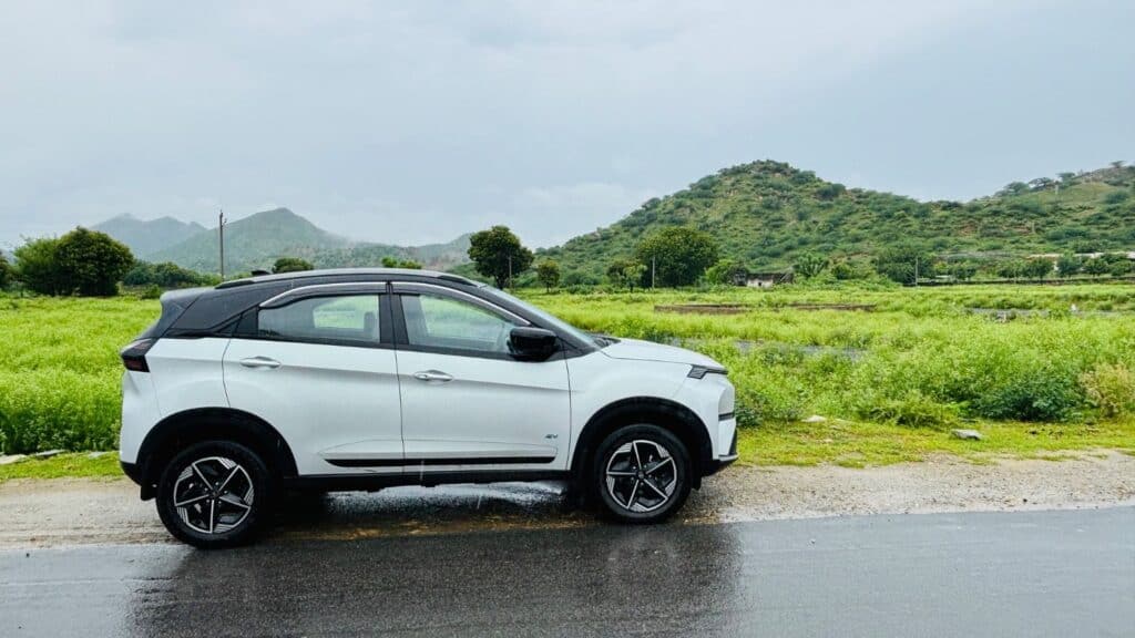 Advanced electric SUV parked on rural road with lush green hills in background, showcasing eco-friendly vehicle design, ideal for off-road adventures and sustainable travel.